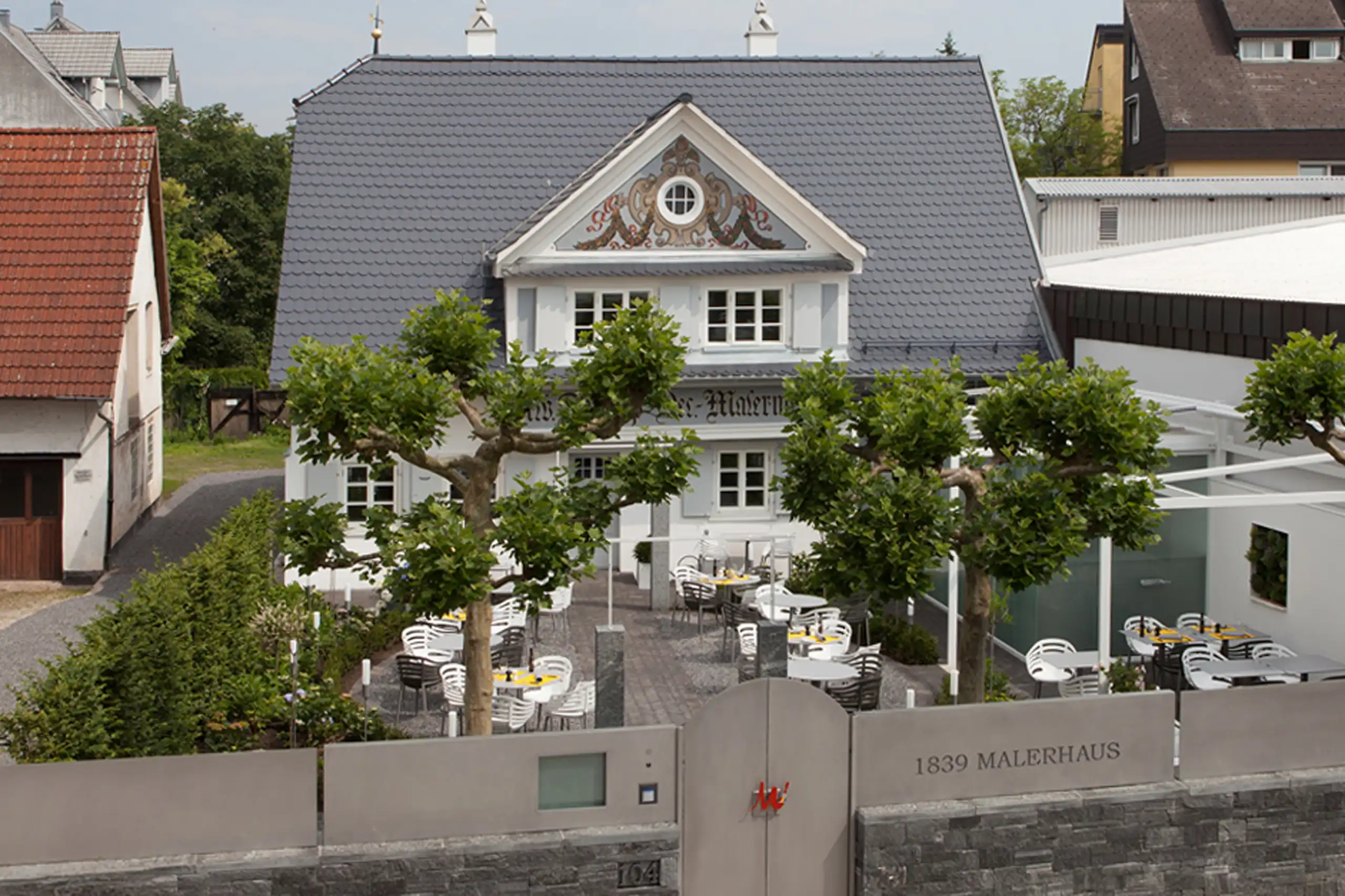 Außenansicht des 1839 Malerhaus Restaurants in Achern mit Terrasse, Tischen und Bäumen vor dem historischen Gebäude